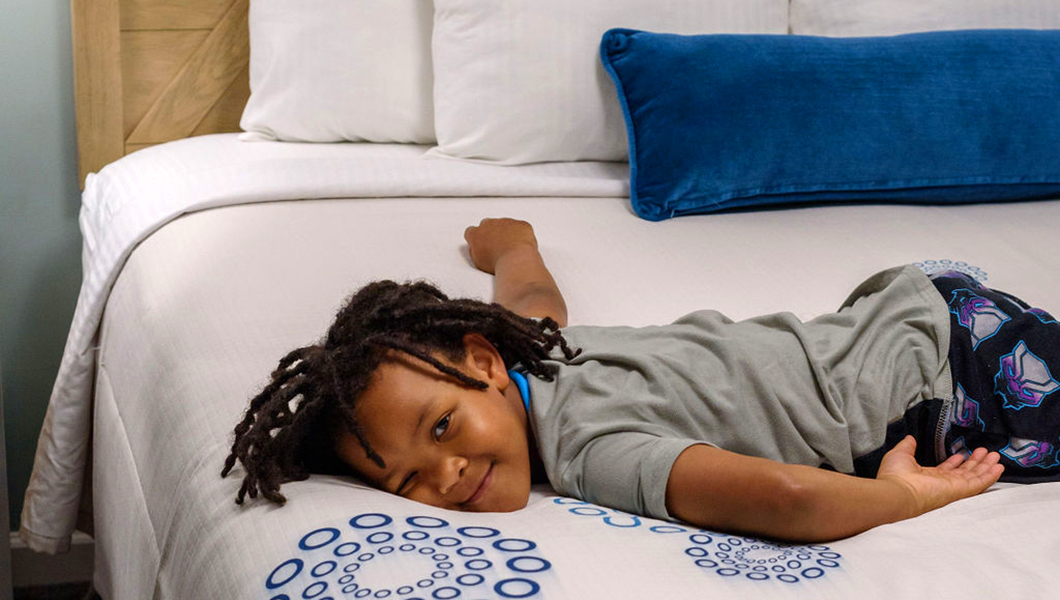 A child playing on a bed in a Woodstone Condo at Massanutten Resort
